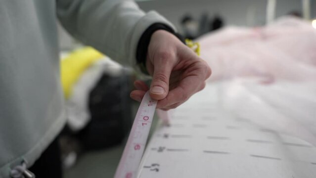 The seamstress measures the fabric with a centimeter tape