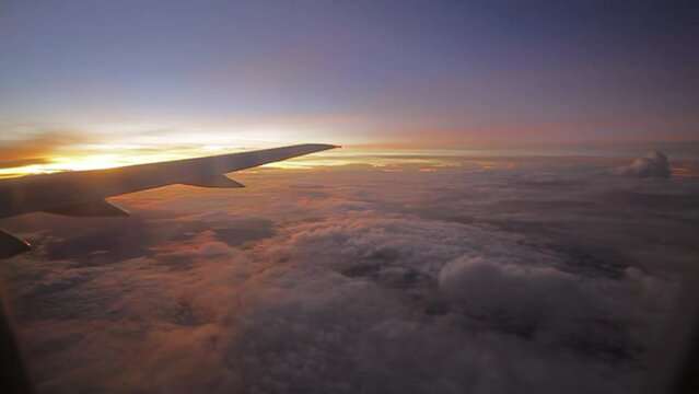 airplane fly onboard low clouds below sunrise purple sky