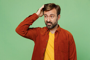 Elderly minded sad mistaken dissatisfied caucasian man 40s years old he wears casual clothes red shirt t-shirt scratch head look aside isolated on plain pastel light green background studio portrait.