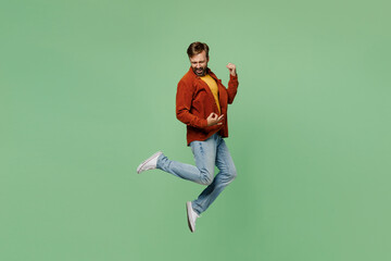 Full body side view elderly man 40s year old he wear casual clothes red shirt t-shirt jump high pretend playing guitar, do hand gesture isolated on plain pastel light green background studio portrait