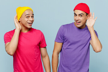 Young curious nosy couple two friends men wear casual clothes looking camera together try to hear...