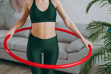 Close up young sporty athletic fitness trainer instructor woman wearing green tracksuit hold using hoola hoop for slim waist training do exercises at home gym indoor. Workout sport motivation concept. © ViDi Studio