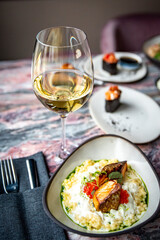white wine glass with grilled salmon fish fillet with creamy ptitim on table