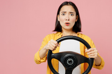 Young sad shocked woman of Asian ethnicity wear yellow shirt white t-shirt hold steering wheel...