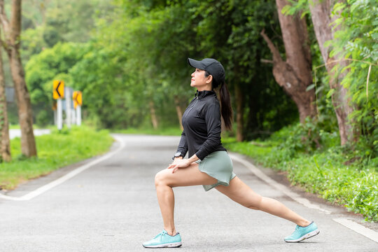 Healthy woman warming up stretching her arms. Asian runner woman workout before fitness and jogging session on the road nature park. Healthy and Lifestyle Concept