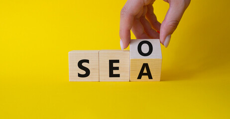 SEO vs SEA symbol. Businessman hand Turnes cube and changes word SEA to SEO. Beautiful yellow...