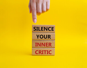 Silence your inner critic symbol. Wooden blocks with words Silence your inner critic. Beautiful yellow background. Businessman hand. Business and Silence your inner critic concept. Copy space.