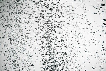 A lot of dark air bubbles of different sizes underwater on a white isolated background. Close up of...