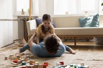 Playful sweet daughter kid resting dads chest, laughing, playing fighting game. Father lying on back on warm carpeted floor cuddling, caressing sweet child, enjoying fatherhood, playtime, leisure
