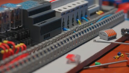 Electrical panel with many red and blue wires, electrical parts, automatic switches, breakers, residual current devices. Close up of a electrical switch on a table in an electrical workshop.