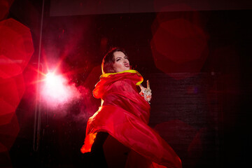 Witch woman in red cloak with skull on black background and light in night. Female warrior in the...