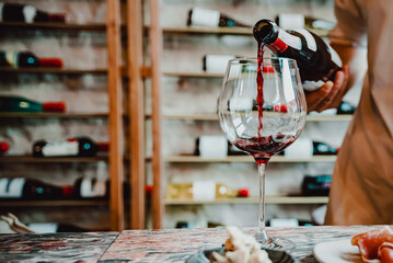 Waiter pouring red wine in glasses for wine on the table in restaurant