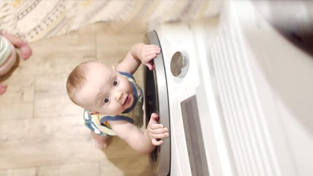 baby decided to explore the washing machine. family a kid dream concept. baby play with washing machine in water. The amazing adventures of a toddler baby explorer with a washing machine lifestyle