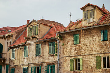 Traveling by Croatia. Ancient architecture of Split old town. Old stone house with green shutters and res tiled roof.