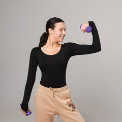 Fitness model exercises with dumbbells and drinks water from a sports bottle