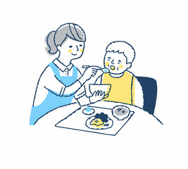 シニア女性の食事介助をしている介護スタッフ