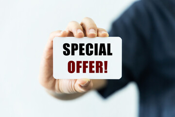 Special offer text on blank business card being held by a woman's hand with blurred background. Business concept about best deal.