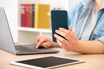 Fototapeta premium Close up of student girl hands using multiple devices sitting on a desk at home