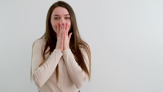 surprise joy the girl covered face with her hands laughing joyful eyes the girl looks into the frame laughing smiling long hair white background pleasant emotions positive