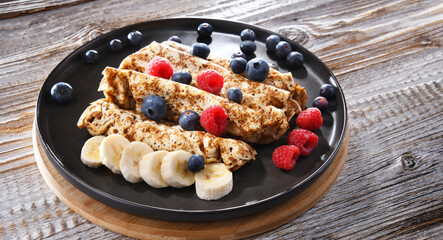 A plate of pancakes with cheese and fruits