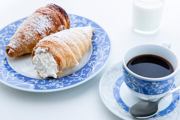 snack with puff pastry cannoli filled with whipped cream and a cup of coffee, still life on white background , close-up