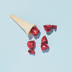 Cherry flavor bonbons spilled from ice cream cone, creative candy layout, summer holidays idea.