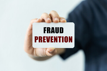 Fraud prevention text on blank business card being held by a woman's hand with blurred background. Business concept about prevention of fraud, scam and phishing.