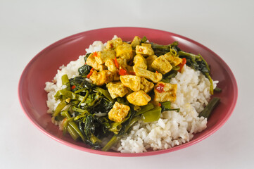 stir-fried water spinach with sliced tofu and white rice served on a red plastic plate