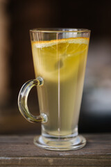 Classic green tea in glass with slice of lemon on wooden table