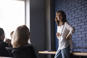 Happy business presenter woman talking to employees on meeting, joking, laughing, discussing...