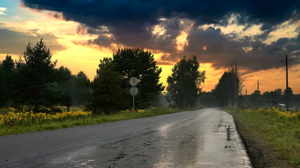 Asphalt road among the fields at sunset. Summer sunset with road.