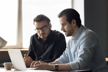 New app developer man presenting software product to client, customer on laptop, showing virtual presentation, typing on computer keyboard. Businessmen using pc at office workplace