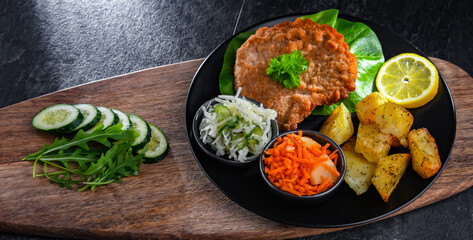 Pork cutlet coated with breadcrumbs with potatoes and salads