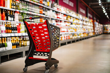 A shopping cart with grocery products in a supermarket - obrazy, fototapety, plakaty