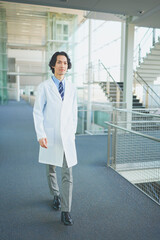 白衣を着て病院の廊下を歩く若い男性医師