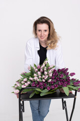 A lovely girl leaned over a table with different varieties of tulips. Bouquet of purple tulips