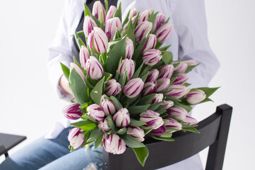 A large bouquet of tulips of different colors in the hands of a woman