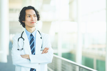 総合病院の廊下で腕組みをする若い男性医師