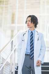 Fototapeta premium 病院の階段を歩く白衣を着た若い男性医師