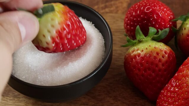 gros plan sur une fraise tremp&eacute;e dans un ramequin de sucre