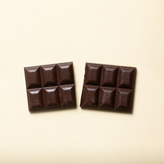 Halved dark chocolate bar, cocoa, handmade and nutritious without additives, on beige smooth...