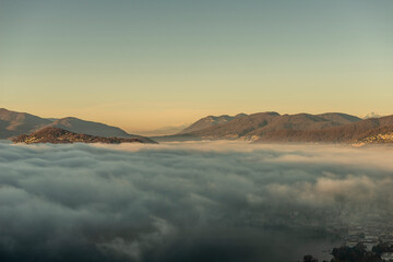 Mountain Range Above Cloudscape and Lake Lugano with Sunlight and Clear Sky in City of Lugano,...