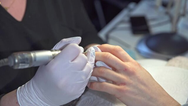 beautician removes cuticles from client's nails