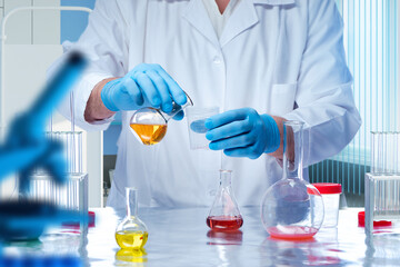 Fototapeta premium Laboratory assistant with test tubes. Scientist in white robe. Cropped laboratory technician. Man near table with flasks. Laboratory technician conducts chemical experiments. Employee medical center