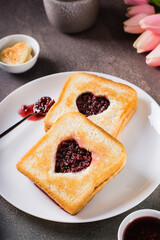 Toast with a heart filled with raspberry jam on a plate. Breakfast for a couple. Vertical view