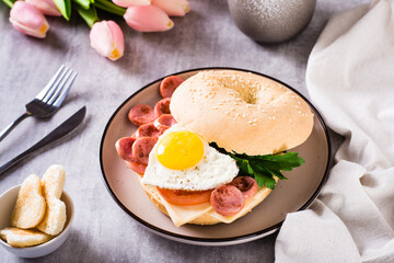 Fried egg heart, tomatoes, cheese and parsley in a bagel on a plate. Romantic breakfast.