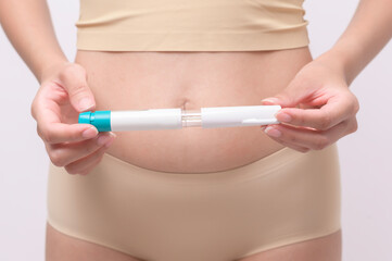 Close up woman using IVF treatment injection on belly to prepare reproductive fertility , Ovulation stimulation ..