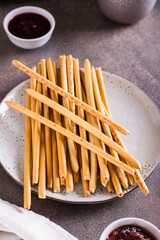 Crispy toasted sweet straws with berry jam on a plate for dessert. Vertical view