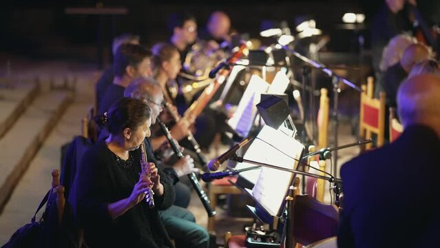 Chamber Music blowing instruments players orchestra perform public no ticketing clasic music event on city square at night, slow motion cinematic shot