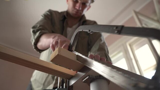male craftsman works in a workshop with wood. sawing a plank. slow motion.